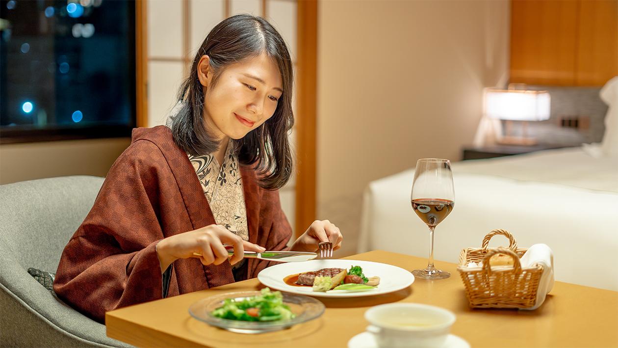 女性が客室で洋食ディナーを食べている。