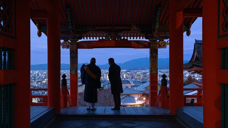 早朝の清水寺で僧侶の案内のもと通常非公開の場所から街を眺める男性