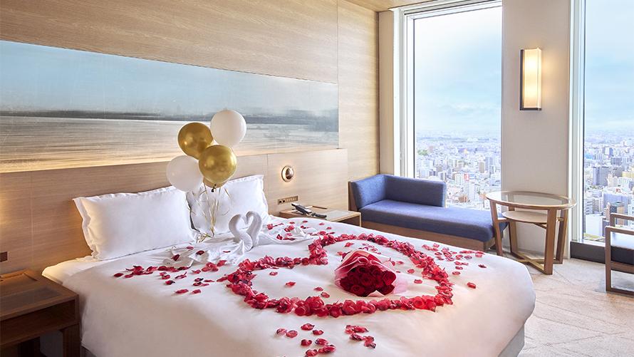 プロポーズプラン。ベッド上にバラの花束と、タオルスワン、バラの花びらの装飾