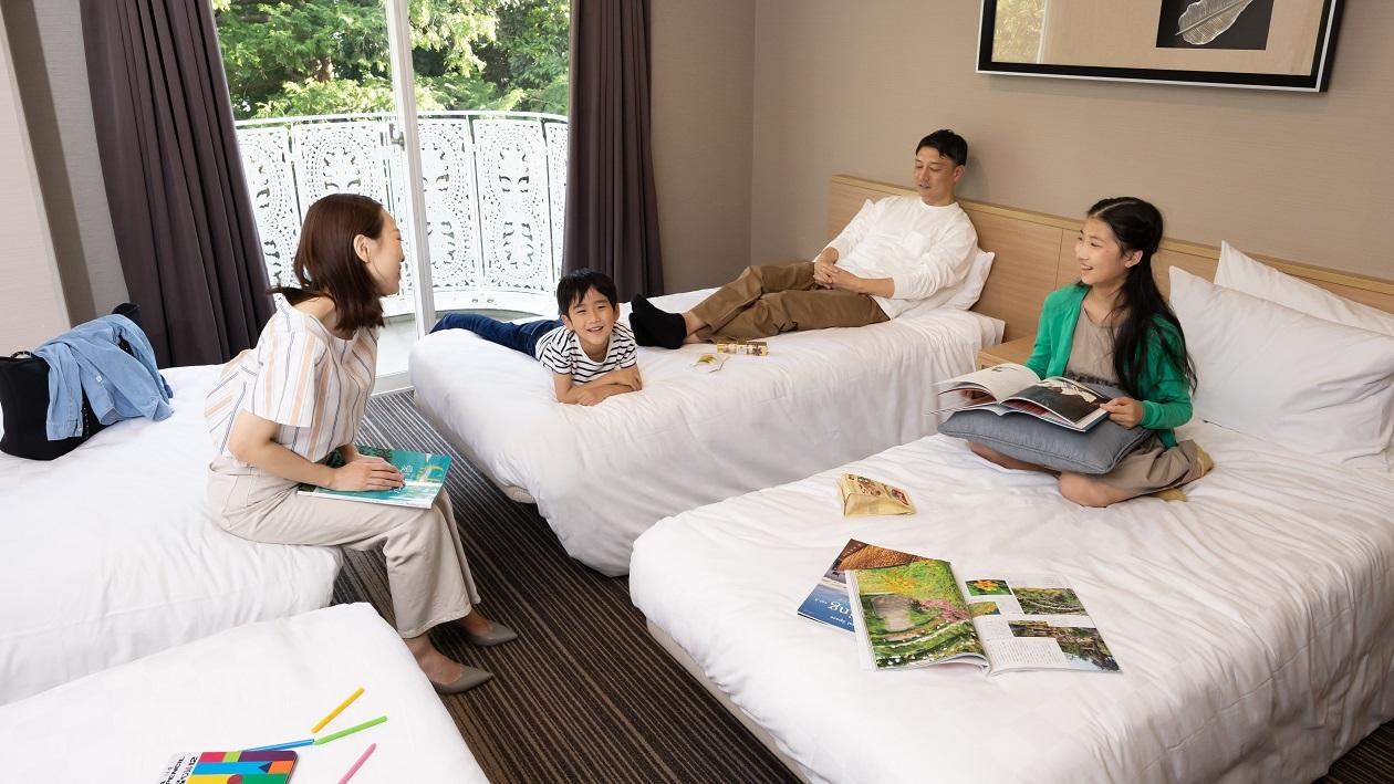 家族4人が4名用の客室で、ベッドの上でくつろいでいる。